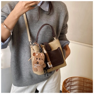 Fashionable beige and brown bucket bag with a plush dog charm on a female model