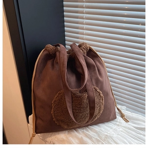 Close-up of vintage brown suede tote featuring a fuzzy plush heart patch and drawstring detail