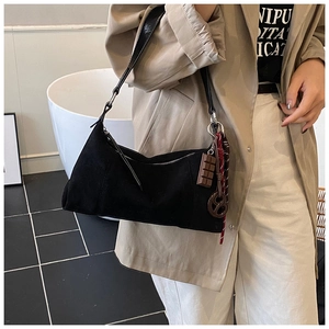 Détail du sac porté épaule en daim noir avec breloque chocolat et ruban à carreaux
