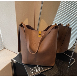 Détail du sac seau en cuir grainé marron foncé avec un fermoir pivotant doré de style vintage