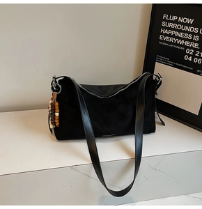 Gros plan du sac bandoulière en daim noir avec finitions cuir et pendentif perles en bois