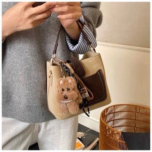 Detail of a beige and brown leather handbag with a cute plush puppy charm accessory