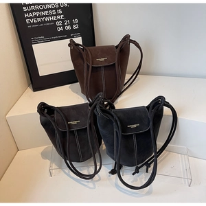 Gros plan de sacs seaux en daim minimalistes en marron, gris et noir avec cordon de serrage