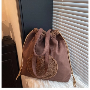 Close-up of brown suede tote bag featuring a fleece patch and cream drawstring closure