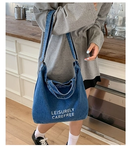 Détail du sac cabas en denim bleu avec texte blanc imprimé et bandoulières robustes
