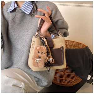 Detail of vintage beige bucket bag featuring brown pocket and cute plush puppy charm