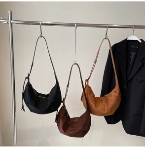 Three suede hobo bags in black, chocolate, and caramel colors on stainless hangers