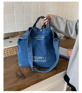 Détail du sac fourre-tout en jean bleu montrant une impression blanche sur bois naturel