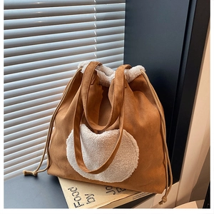 Detail of caramel suede tote bag with white faux fur heart decor and side drawstring