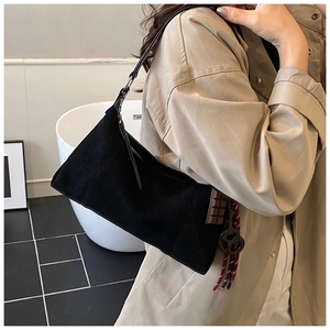 Détail du sac à bandoulière en daim noir avec pendentif chocolat et cordon tressé