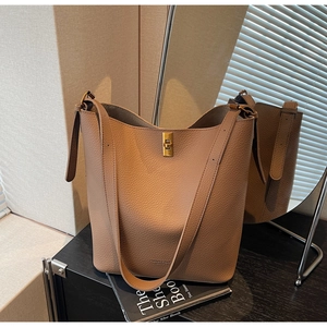 Détail du sac seau en cuir grainé marron avec fermoir tournant doré et texte de mode
