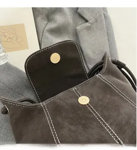 Gros plan d'un sac seau en daim marron avec surpiqûres blanches et boucles magnétiques