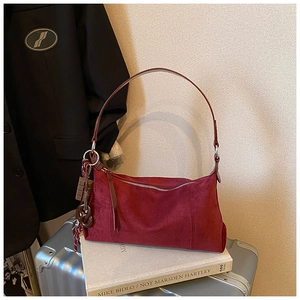 Détail du sac bandoulière en daim bordeaux avec breloques sur fond rétro chic