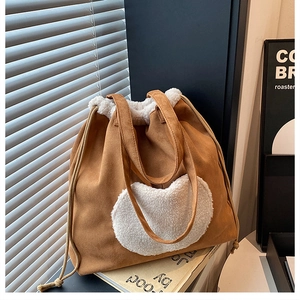 Detail of suede tote bag with white faux fur heart pocket and drawstring closure