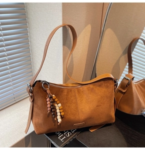 Vue détaillée de la surface en daim marron et du pendentif de perles bohèmes sur le sac porté épaule