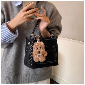 Detail of black matte bucket bag with white contrast stitching and plush dog charm
