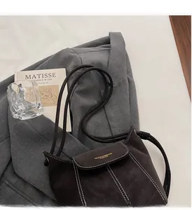 Gros plan du sac seau en daim mat avec coutures contrastées et marquage de la marque
