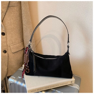 Gros plan du sac à bandoulière en daim noir avec pendentifs chocolat et bretzel uniques