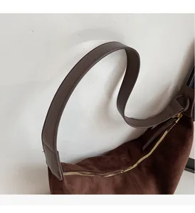 Detail of soft brown suede texture and sturdy leather strap with golden zipper closure