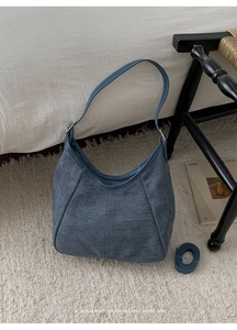 Détail d'un sac seau en daim bleu marine avec surpiqûres et bandoulière supplémentaire