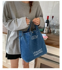 Vue détaillée du sac cabas en jean bleu avec texte sur fond de cuisine rustique