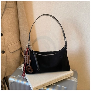 Détail du sac hobo en daim noir avec breloques créatives en forme de biscuit