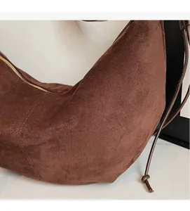 Close-up of brown suede fabric texture and durable stitching on a crescent shoulder bag