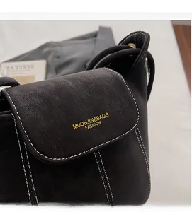 Détail du sac seau en daim noir avec surpiqûres blanches et marquage doré élégant