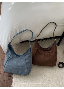 Gros plan de sacs seaux minimalistes en daim bleu-gris et cuir marron café foncé