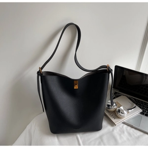 Détail du sac seau en cuir grainé noir avec boucle dorée et bandoulière minimaliste