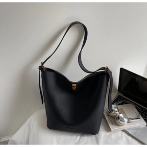 Détail du sac seau en cuir grainé noir avec fermoir doré dans une scène de style bureau