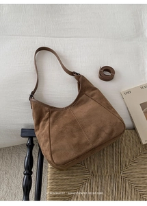 Détails de la texture du sac hobo en daim marron et de la bandoulière réglable incluse