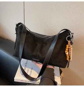 Gros plan d'un sac bandoulière noir mat en daim avec un pendentif en perles bohèmes