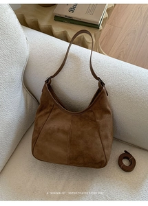 Détail du sac seau en daim marron avec poignée large et longue bandoulière assortie