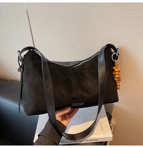 Détail du sac à bandoulière en daim noir avec bordure en cuir et pompon perlé coloré
