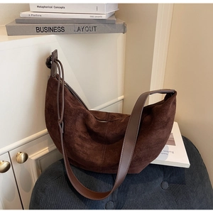 Close-up of a dark brown suede hobo bag with leather trim and metal zipper detail