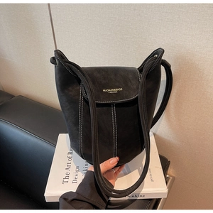 Détail du sac seau en daim noir avec surpiqûres blanches contrastées et logo doré