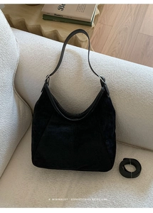 Détail du sac hobo en daim noir sur canapé blanc avec boucle en métal réglable