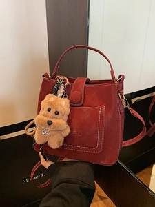 Vintage burgundy suede bucket bag with hand strap, cross-body chain and dog charm accessory