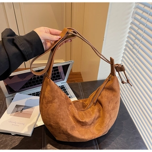 Detailed close-up of a caramel brown suede hobo bag with zipper and wide strap