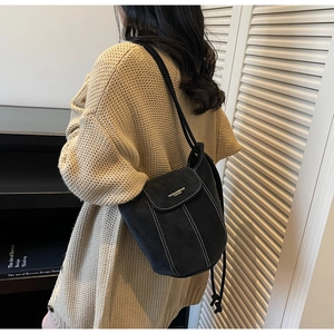 Détail du sac seau en daim noir avec surpiqûres blanches contrastées et rabat chic
