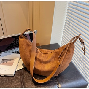 Close-up of crescent suede shoulder bag showing matte texture and knotted zipper detail