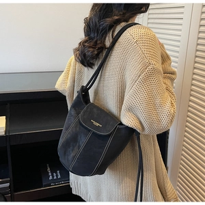 Détail du sac seau noir en daim avec surpiqûres contrastées et logo de marque en cuir