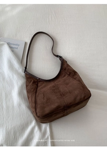 Détail d'un sac hobo en daim marron foncé avec coutures vintage et bandoulière réglable