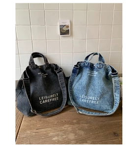 Détail de sacs cabas en denim gris et bleu avec texte imprimé et fermetures à boucle métal