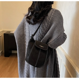 Vue détaillée du sac seau noir en daim mat avec surpiqûres blanches sur le mannequin