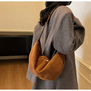 Detailed view of brown suede hobo bag on shoulder showing soft texture and premium finish