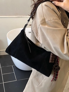 Sac bandoulière en daim noir avec breloque chocolat et gland tissé sur trench-coat