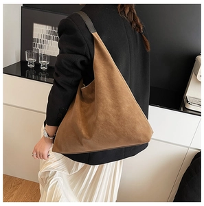 Detail of large brown matte suede tote bag with black leather strap on a shoulder