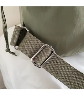 Detail of adjustable nylon shoulder strap with silver metal buckle on army green bucket bag
